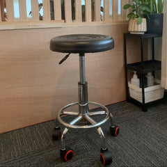 Black stool with wheels in a room with a wooden partition and plants.