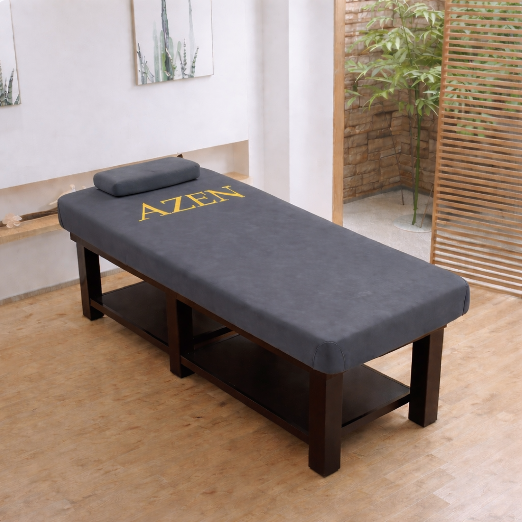 Massage table with 'AZEN' branding in a room with wooden floor and plants.