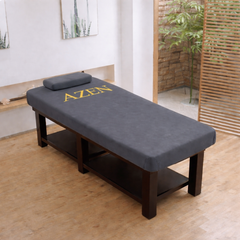 Massage table with 'AZEN' branding in a room with wooden floor and plants.